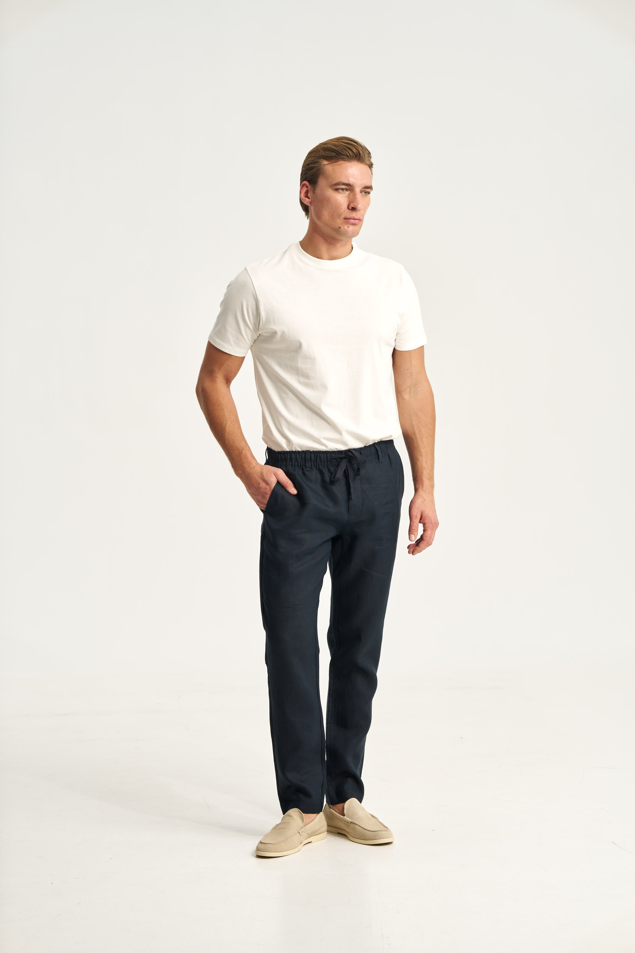 Man wearing a white t-shirt and dark pants on a white background